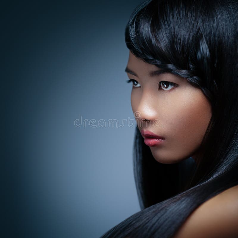 Beautiful Asian woman with a braid in her hair posing in front of a blue background.