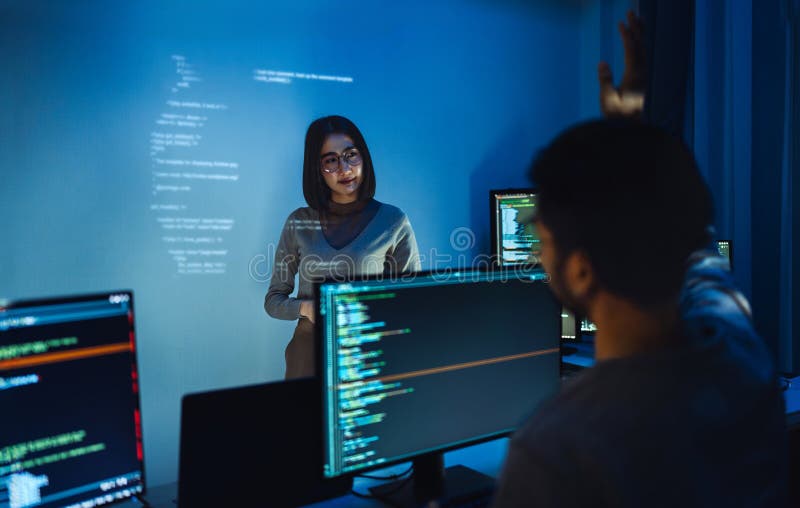 Asian woman developers collaborating on a coding project, with one member presentation at code projected on the wall while the stock image