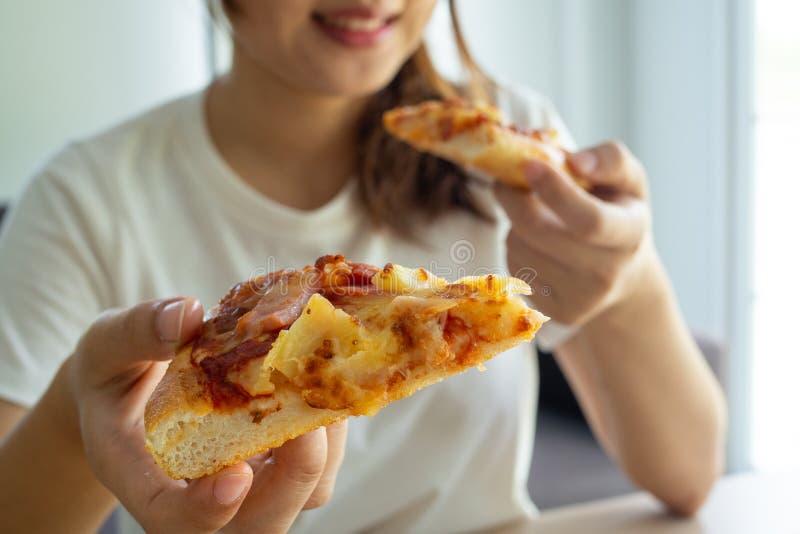 An Asian woman is eating a pizza he ordered. During the break, enjoy Italian pieces with delicious cheese at home