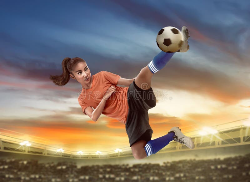 Asian woman football player kick ball on the stadium