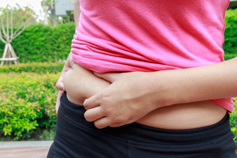 Asian woman hand holding belly fat in the park