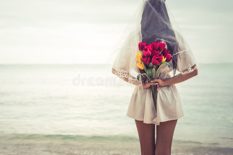 Asian woman holding flowers in behind and waiting for someone ma