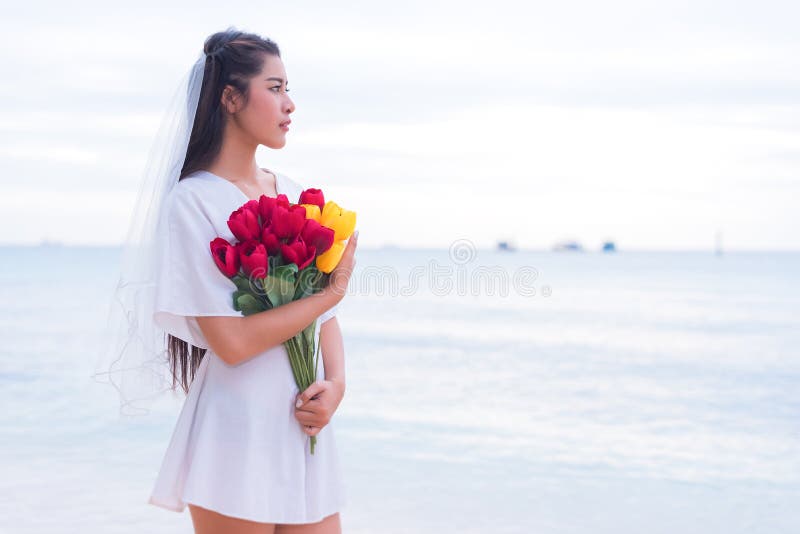 Asian woman holding flowers and waiting for someone make her hap