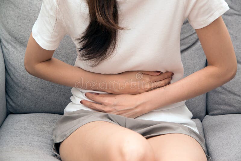 Asian woman holds her stomach with both hands. Stomach upset or pain during menstruation.