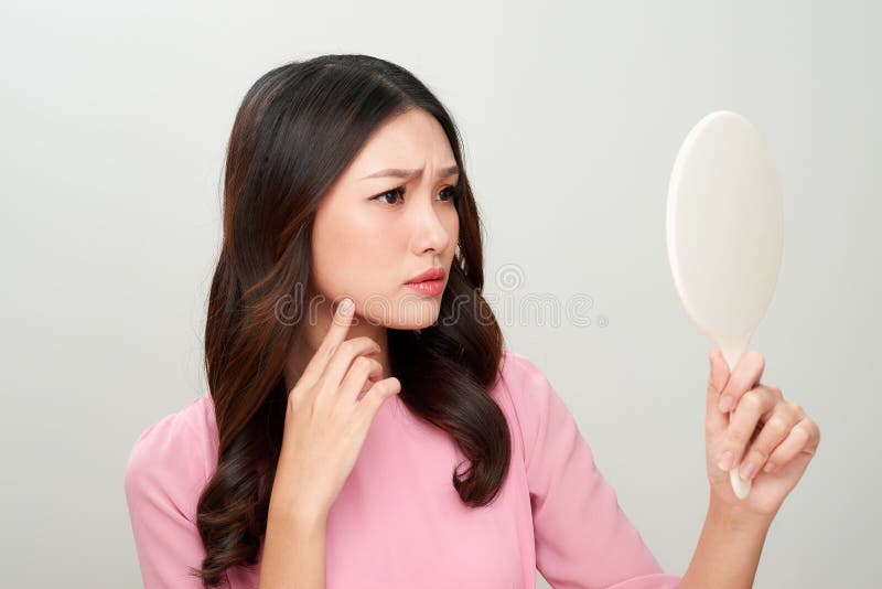 Asian woman looking at the mirror with the trouble on her skin. stock photo Asian woman looking at the mirror with the trouble on her skin. stock photo