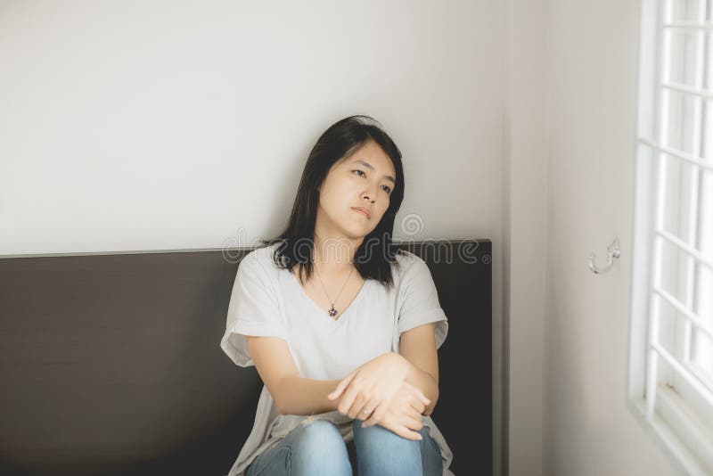 Asian woman looking somthing on window and depression have a headache and feeling sadness in bedroom