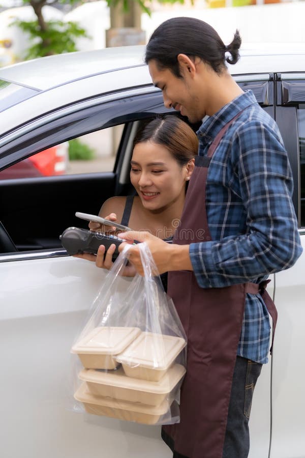 Asian woman making contactless payment with credit card for take out drive thru food