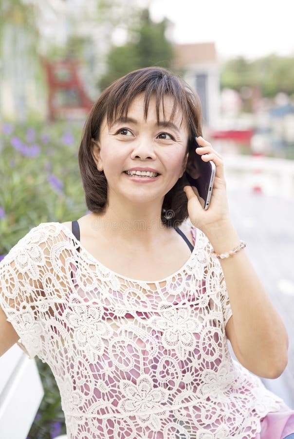 Asian woman phoning at home in garden stock image Asian woman phoning at home in garden stock image