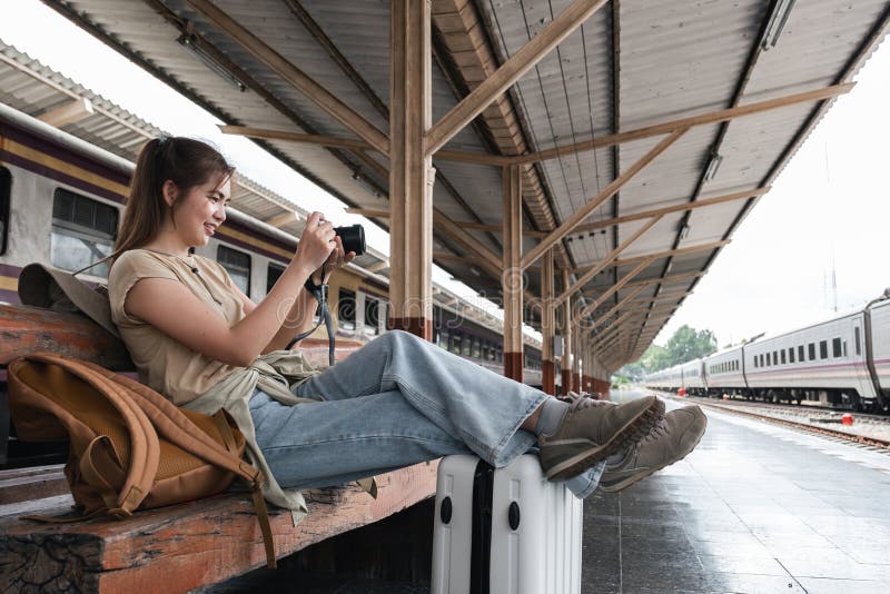 Asian woman photographing while waiting at train station, concept of creativity royalty free stock photography