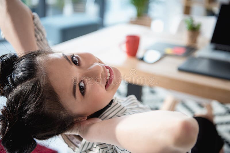 Asian woman relaxing and looking at camera while sitting at office royalty free stock photo