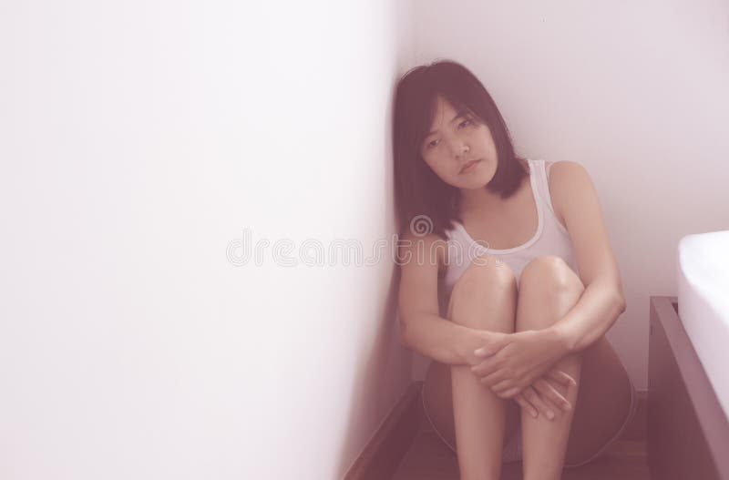 Asian woman sits and hugs his knees up to the chest depression have a headache in her bedroom