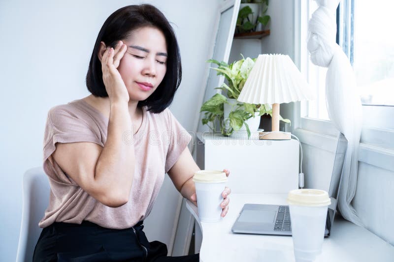 Asian Woman Suffering from Headache after Drinking Coffee Stock Image
