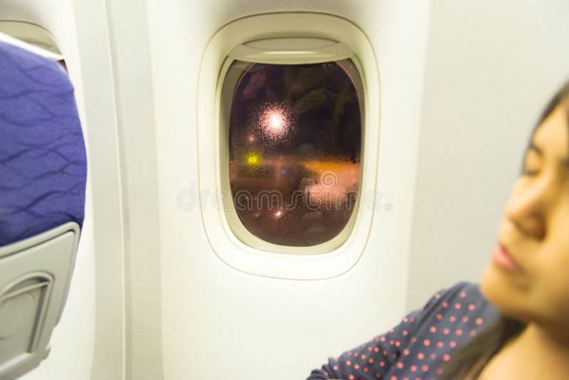 Asian woman traveller sleeping siting near window on airplane during flight