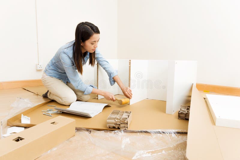 Asian woman using hammer for assembling furniture stock photo