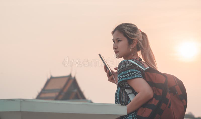 Asian woman using mobile while traveling in Bangkok Chao Phraya river at sunset royalty free stock image