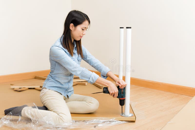 Asian woman using screwdriver for assembling furniture royalty free stock images
