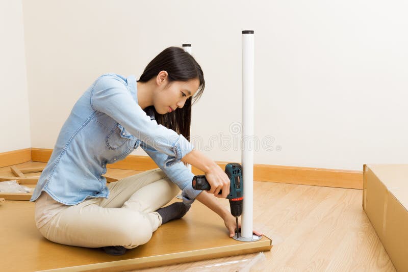 Asian woman using strew driver for assembling furniture stock photo