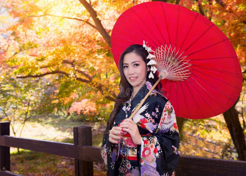 Asian woman wearing traditional japanese kimono with red umbrella.