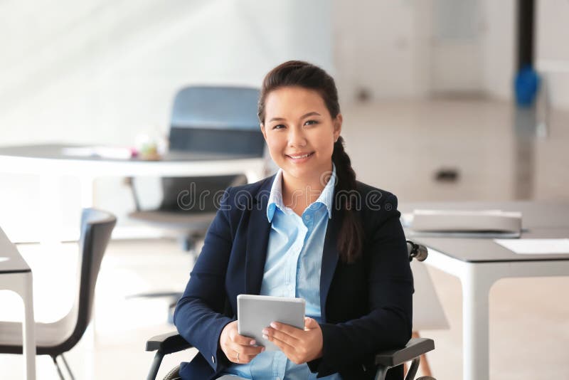 Asian woman in wheelchair working with tablet PC in office royalty free stock image Asian woman in wheelchair working with tablet PC in office royalty free stock image