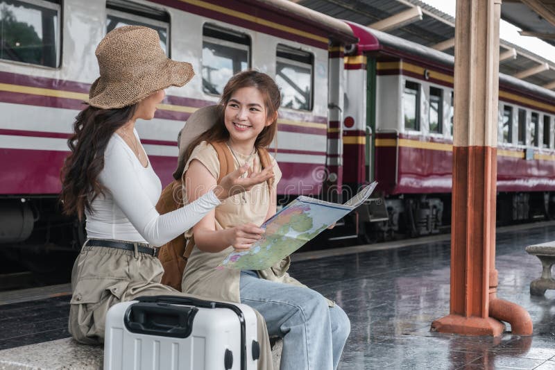 Asian women discussing travel plans with map at train station, concept of adventure royalty free stock photos