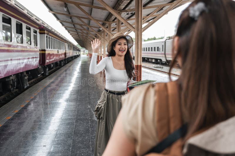 Asian woman waving at friend at train station, concept of reunion royalty free stock photo