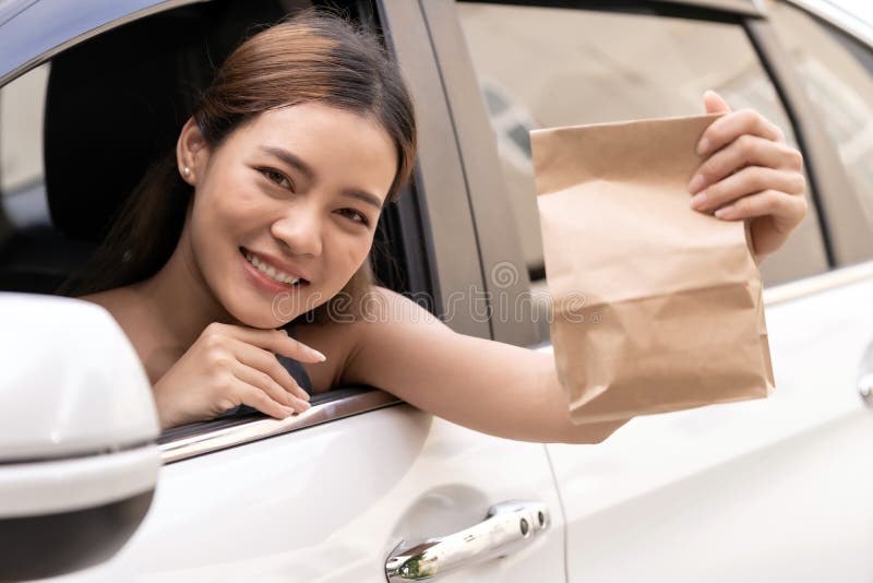 Asian woman holding food bag from drive thru service restaurant