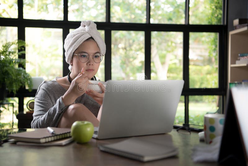 Asian young woman in casual clothing using laptop and smiling while working from home stock photo Asian young woman in casual clothing using laptop and smiling while working from home stock photo