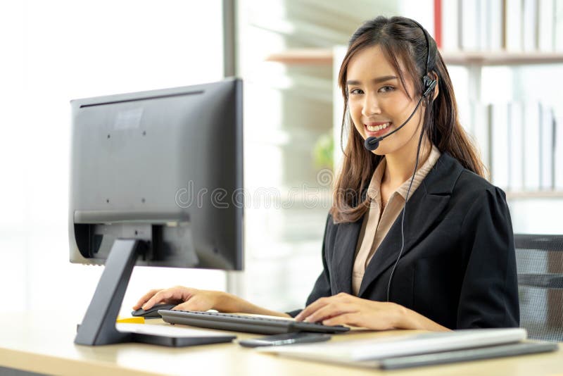 Asian young woman working in call centre. Young friendly operator woman agent with headsets working in a call centre