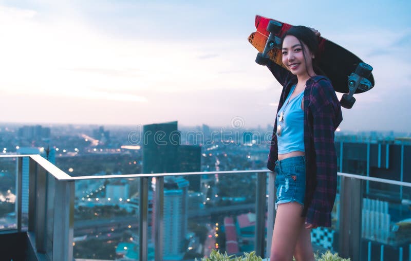 Asian young women surf skate or skates board outdoors on beautiful summer day. Happy young women play surf skate at roof top