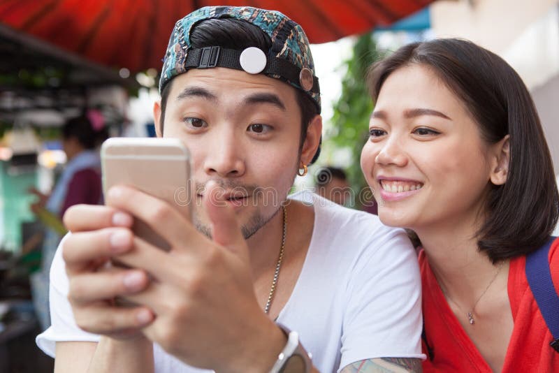 asian younger man and woman watching on smart phone use for people and digital technology ,wifi and internet connection