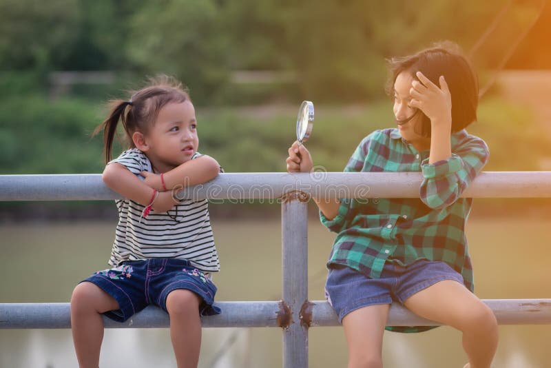 Asianisches kleines Mädchen benutzt Lupe, um in der Parkhaus zu spielen stockfotos