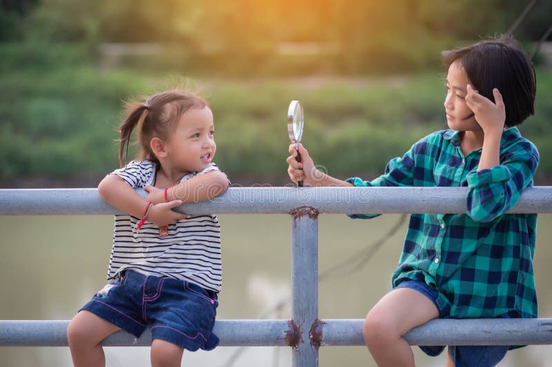 Asianisches kleines Mädchen benutzt Lupe, um in der Parkhaus zu spielen lizenzfreies stockbild