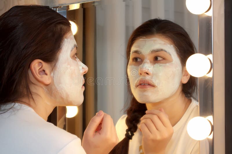 Asiatin, Die Maske Auf Ihrem Gesicht Anwendet Und Im Spiegel Schaut