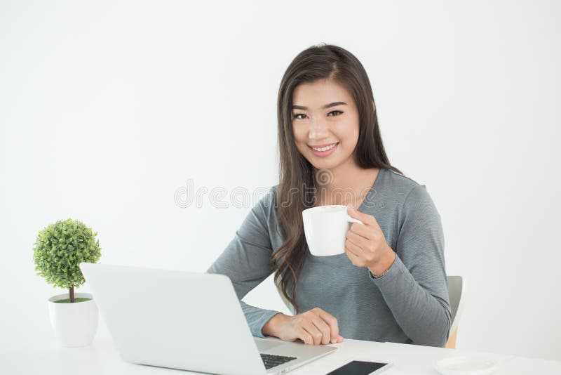 Asiatinnen sitzen das L?cheln am Schreibtisch Sitzendes trinkendes happil Kaffee der Frau stockbilder Asiatinnen sitzen das L?cheln am Schreibtisch Sitzendes trinkendes happil Kaffee der Frau stockbilder