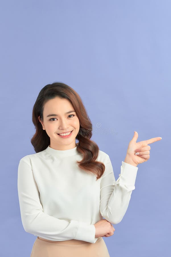 Asiatique jeune femme debout fait un geste les doigts pointent vers le haut au-dessus de présenter le produit quelque chose photo stock
