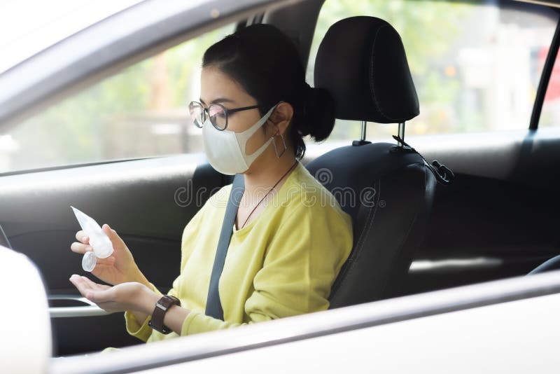 Asiatische Frauen in grünen oder gelben Hemden tragen eine Schutzmaske mit einem Handsanitizer-Gel auf ihren Handflächen, um Coro lizenzfreie stockfotografie