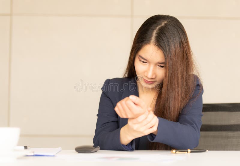 Asiatische Geschäftsfrau, die ihre Handgelenkschmerz vom Funktionieren hält lizenzfreie stockfotografie