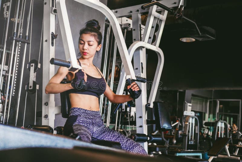 Asiatische junge Eignungsfrau führen Übung mit Übungmaschine durch stockfoto Asiatische junge Eignungsfrau führen Übung mit Übungmaschine durch stockfoto