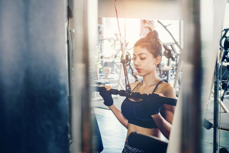 Asiatische junge Eignungsfrau führen Übung mit Übungmaschine durch stockbild Asiatische junge Eignungsfrau führen Übung mit Übungmaschine durch stockbild