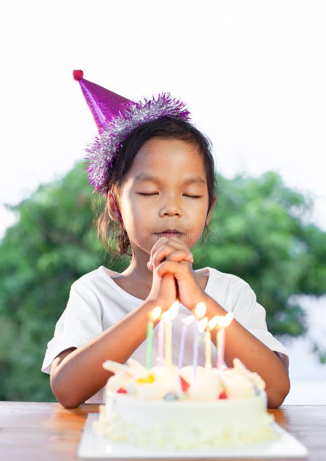 Asiatische Kindermädchen stellen gefaltete Hand her, um die guten Sachen für ihren Geburtstag in der Geburtstagsfeier zu wünschen lizenzfreie stockbilder Asiatische Kindermädchen stellen gefaltete Hand her, um die guten Sachen für ihren Geburtstag in der Geburtstagsfeier zu wünschen lizenzfreie stockbilder