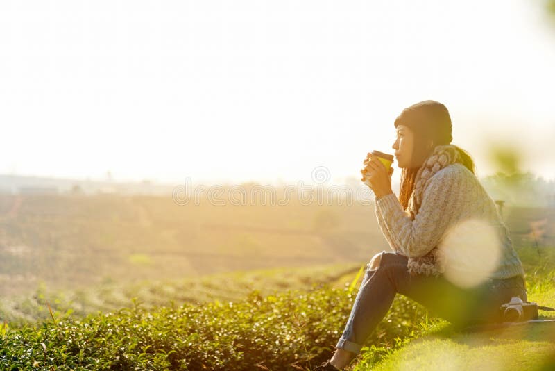 Asiatische Lifestyle-Frauen tragen Pullover, sitzen und trinken heißen Kaffee oder Tee entspannen sich draußen in der sonnigen Mo