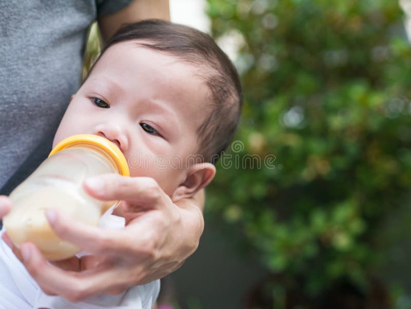 Asiatische Muttersaugflasche ihr Baby im Garten stockfoto Asiatische Muttersaugflasche ihr Baby im Garten stockfoto