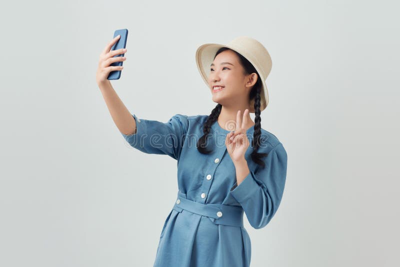 Asiatische Mädchen, die isoliert auf weißem Hintergrund posieren und selftig auf Handy aufsetzen stockbilder