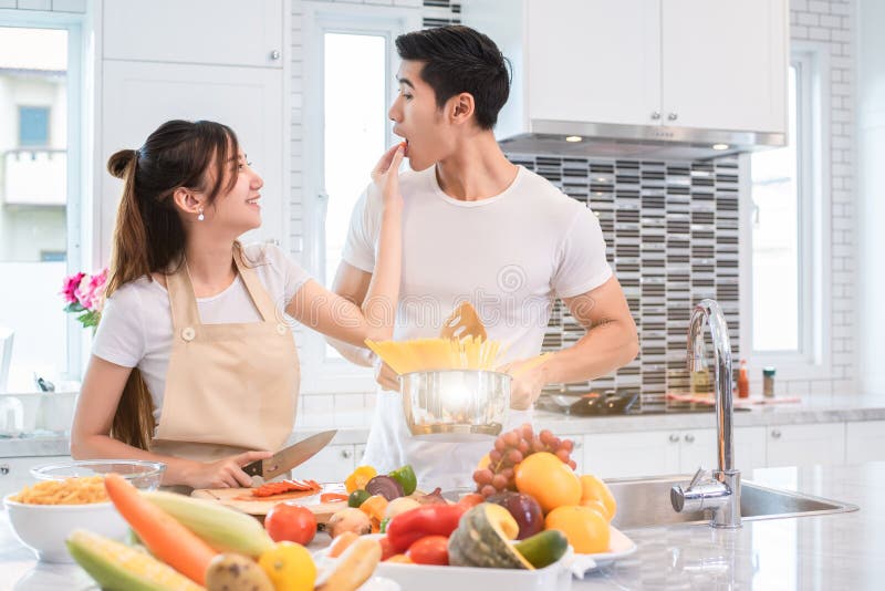 Asiatische Paare, die zusammen Nahrung in Küche einziehen Leute und lifes