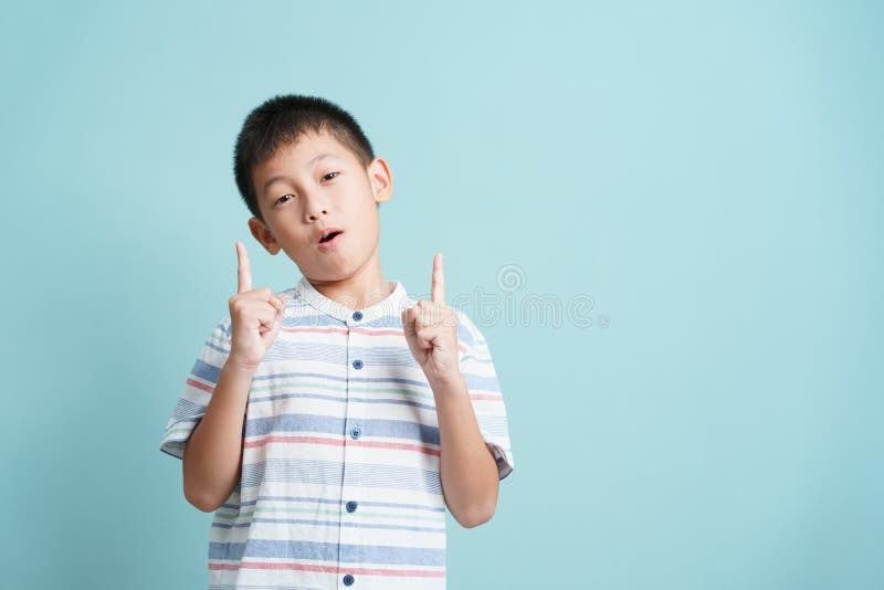 Asian little boy standing thinking on blue background isolated, Portrait of cute man points up. Asian little boy standing thinking on blue background isolated, Portrait of cute man points up.