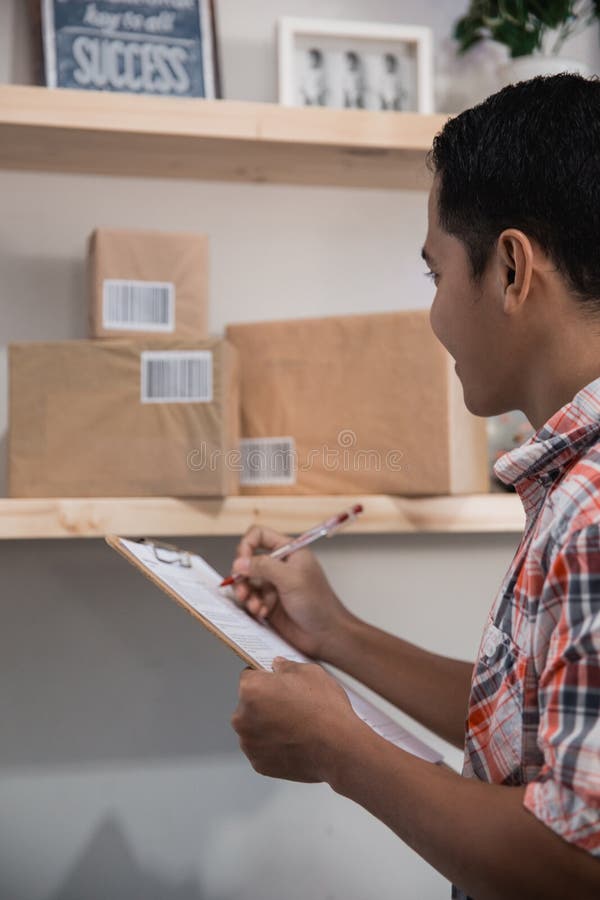 Asiatischer Arbeitskraftblick auf die Kästen auf einem hölzernen Regal im Büroraum und -prüfung lizenzfreie stockfotografie