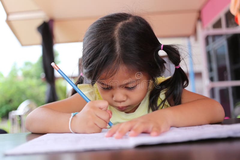 Asiatischer Kindermädchen-Gebrauch Bleistift schreiben Briefe auf dem Buch lizenzfreie stockbilder Asiatischer Kindermädchen-Gebrauch Bleistift schreiben Briefe auf dem Buch lizenzfreie stockbilder