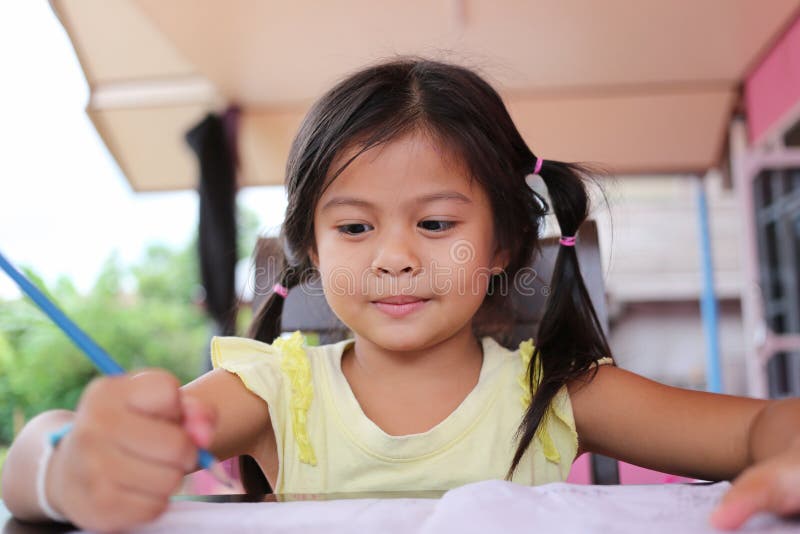 Asiatischer Kindermädchen-Gebrauch Bleistift schreiben Briefe auf dem Buch stockfoto Asiatischer Kindermädchen-Gebrauch Bleistift schreiben Briefe auf dem Buch stockfoto