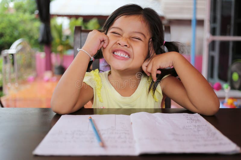 Asiatischer Kindermädchen-Gebrauch Bleistift schreiben Briefe auf dem Buch lizenzfreie stockbilder Asiatischer Kindermädchen-Gebrauch Bleistift schreiben Briefe auf dem Buch lizenzfreie stockbilder