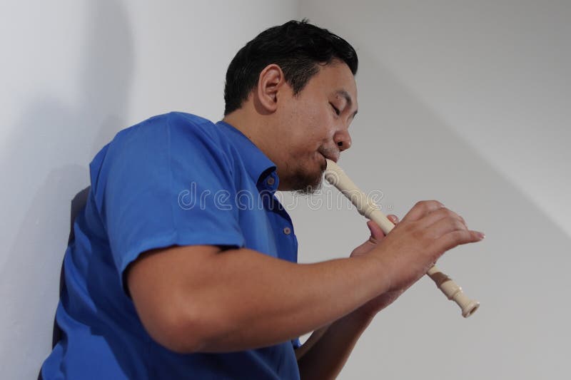 Asiatischer Mann spielt Blockflöte, Musikinstrument lizenzfreie stockfotografie